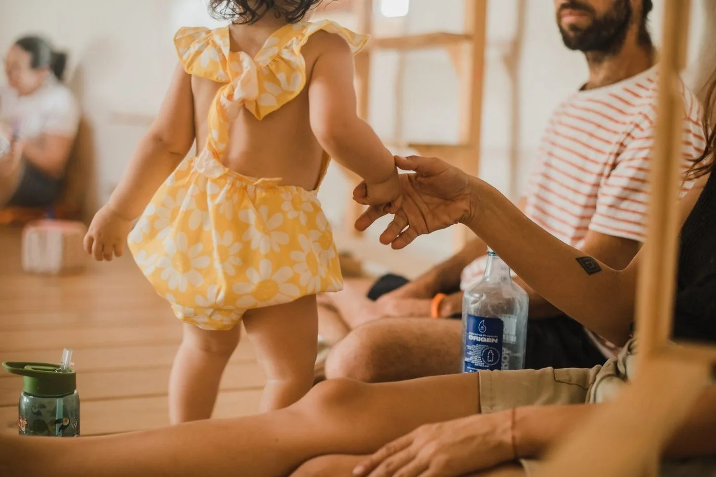 Una niña con un vestido amarillo da la mano a un adulto en una sala de juego