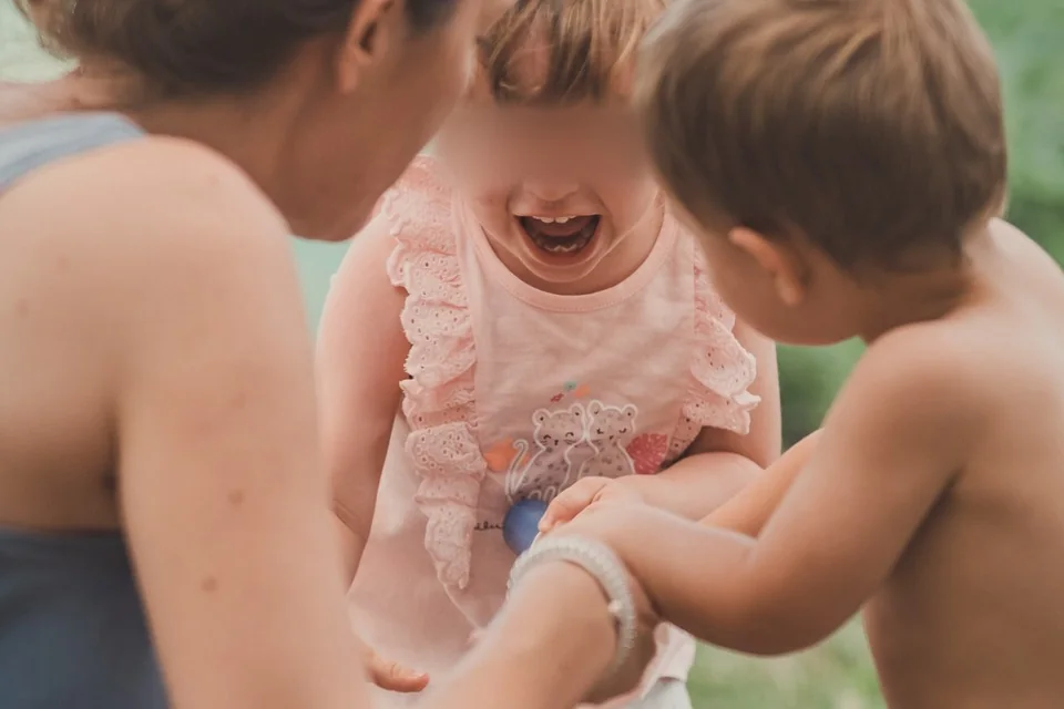 Una niña enfadada entre su madre y otro niño en el parque